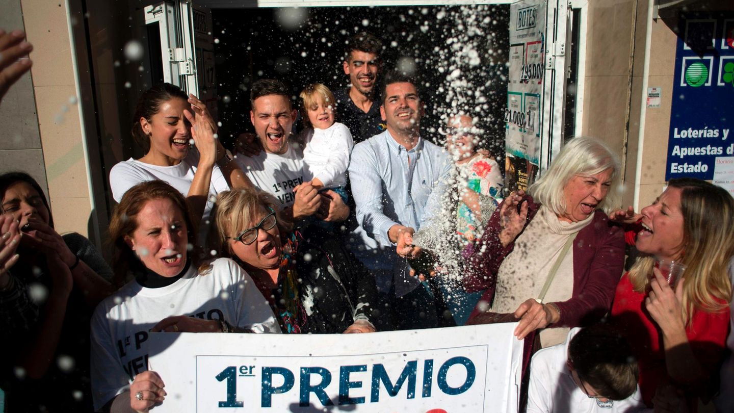 Vor einer Bar in Spanien stehen Gewinner von "El Gordo" mit einem Riesen-Los und verspritzen vor Freude Sekt