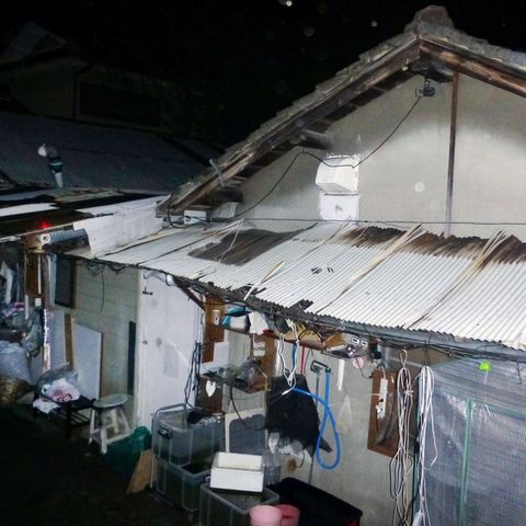 Ein heruntergekommenes Haus mit Wellblechvordach und wilden Verkabelungen steht in Japan