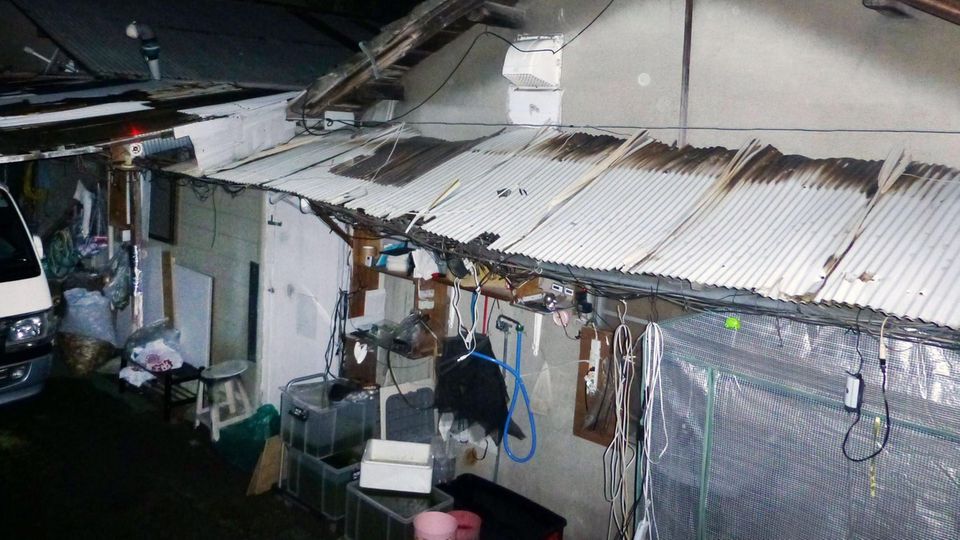 Ein heruntergekommenes Haus mit Wellblechvordach und wilden Verkabelungen steht in Japan