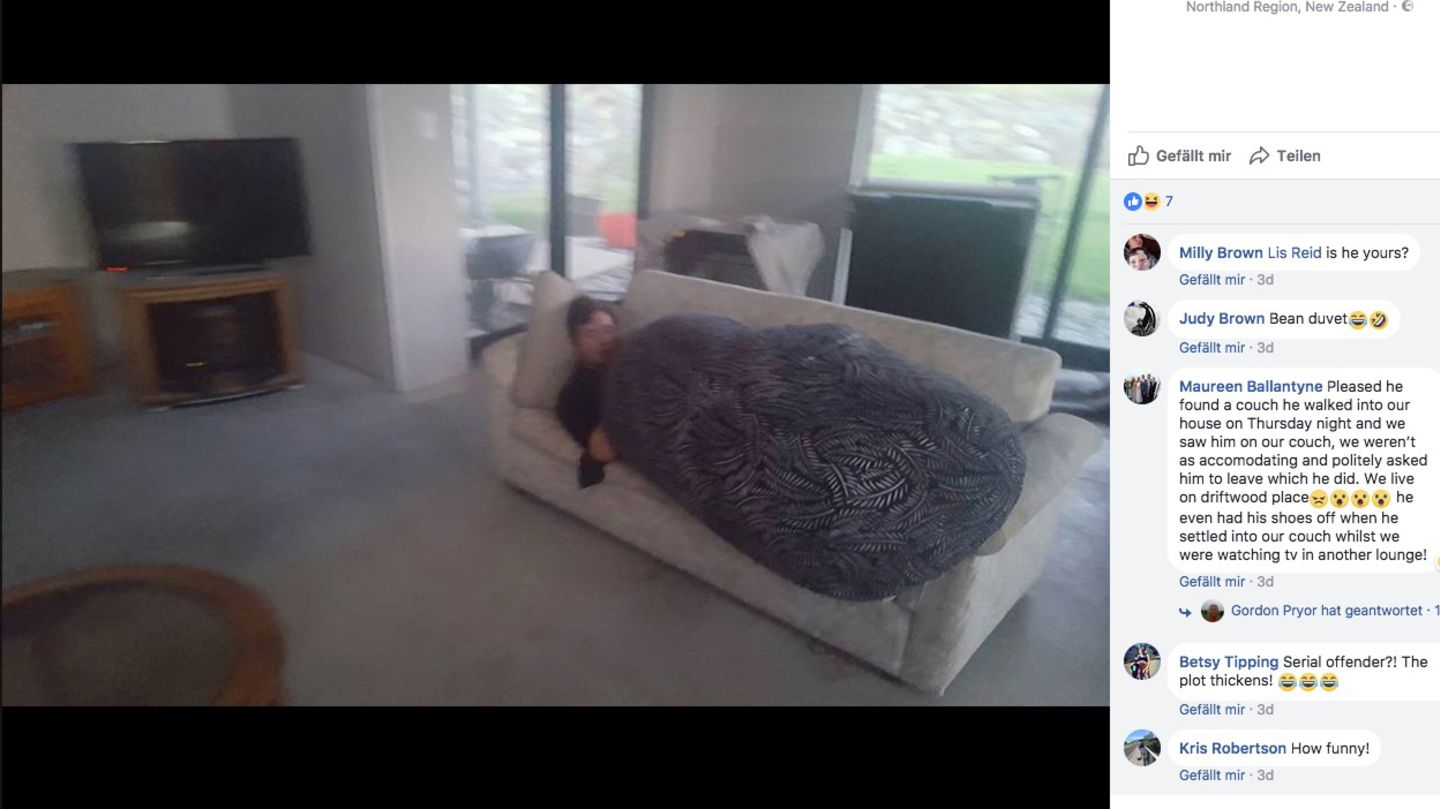 Ein Mann liegt unter einer Decke auf einer Couch und schläft