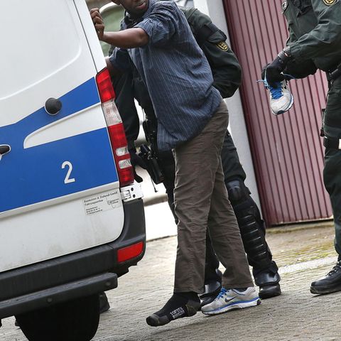 Polizisten untersuchen den Schuh eines Flüchtlings