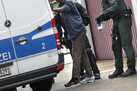 Polizisten untersuchen den Schuh eines Flüchtlings
