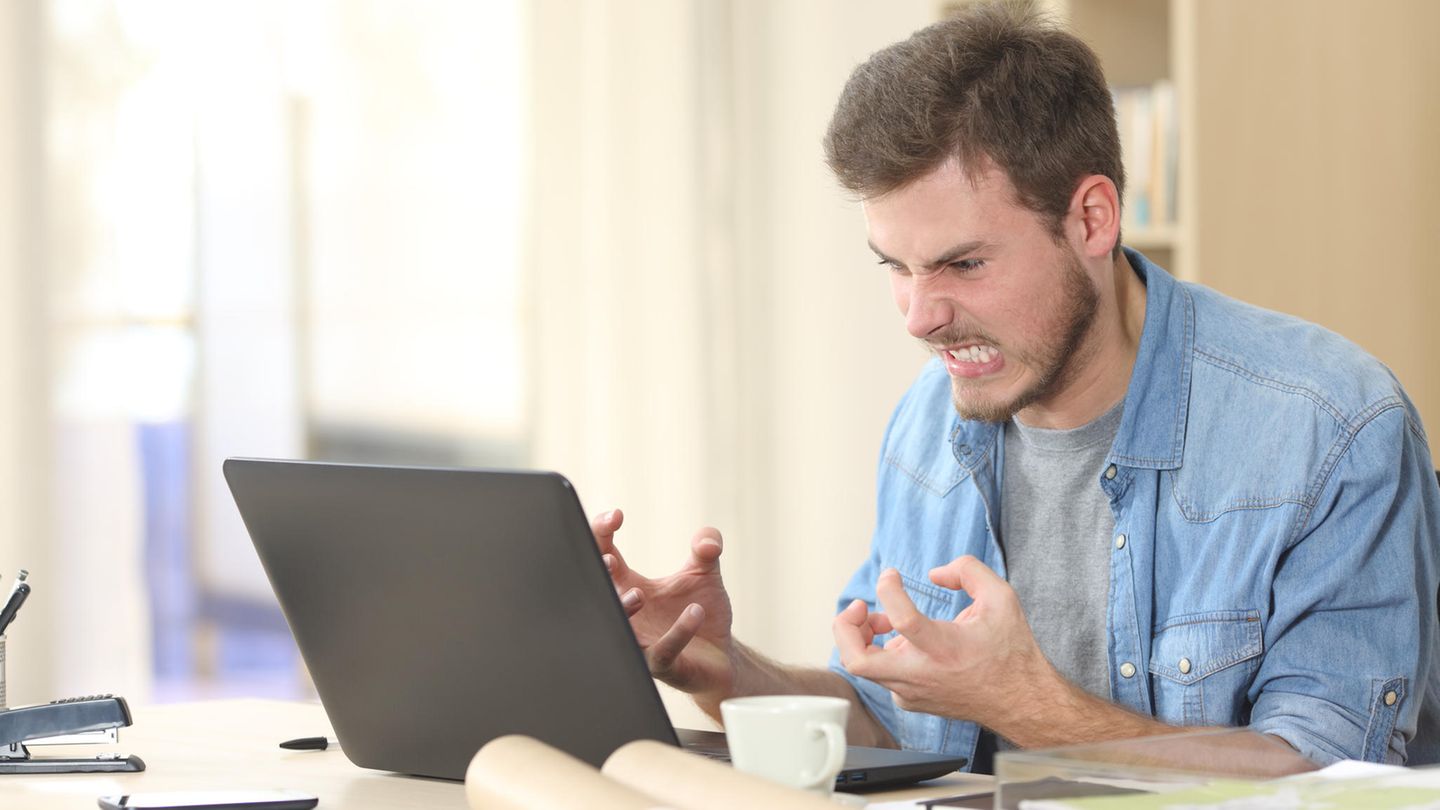 Ein Mann sitzt wütend vor seinem Laptop