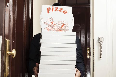 EIn Pizzabote trägt die bestellten Pizzen in eine Wohnung