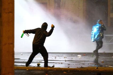 Ein Mann wirft bei Krawallen in Leipzig Flaschen Richtung Polizei - zu Gewalt-Studie