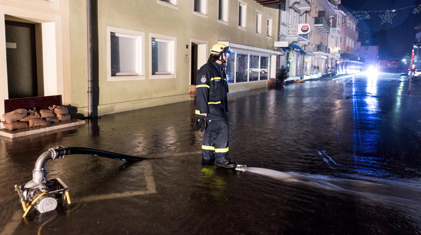 Ein Feuerwehrmann mit Pumpe auf einer überfluteten Straße