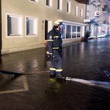 Ein Feuerwehrmann mit Pumpe auf einer überfluteten Straße