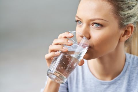 Eine junge Frau trinkt ein Glas Wasser