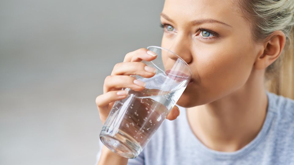 Eine junge Frau trinkt ein Glas Wasser