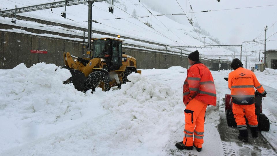 Helfer befreien die Bahnstrecke nach Zermatt vom Schnee, unter anderem mit einem Bagger
