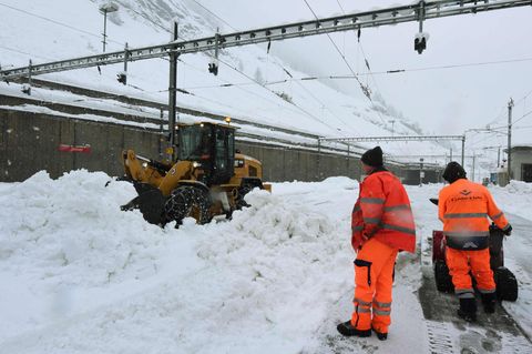 Helfer befreien die Bahnstrecke nach Zermatt vom Schnee, unter anderem mit einem Bagger
