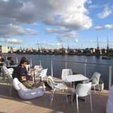 Der schwimmende Flachbau hat für London eine Dachterrasse bekommen, mit Bar und Blick über das Wasser auf die Skyline, die abends rot leuchtenden Kabinen der Gondelbahn über die Themse.