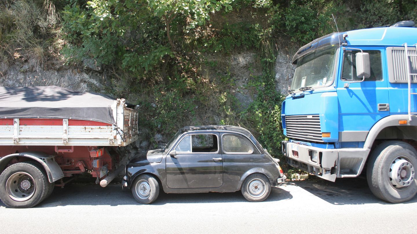 Ein Kleinwagen parkt eingequetscht zwischen zwei Lkw