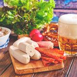 Die wohl bekannteste Spezialität aus München: Weißwurst wird traditionell frühmorgens hergestellt und vormittags als Imbiss auf Märkten und in Wirtshäusern mit süßem Senf, Brezn und Weißbier gegessen. So isst man die Wurst übrigens richtig!