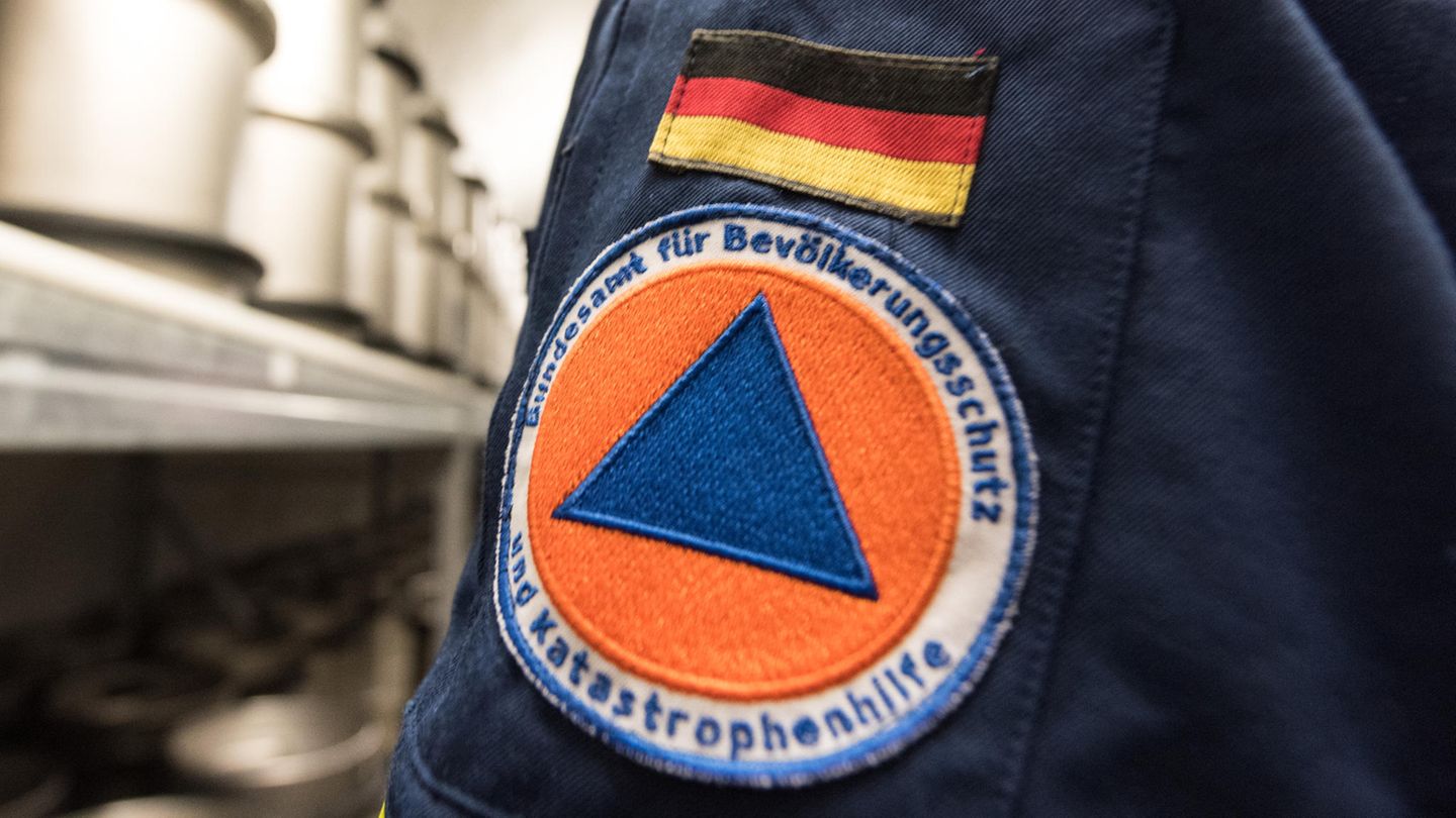 Auf dem Ärmel einer dunkelblauen Uniform ist eine aufgenähte Deutschlandflagge und darunter das Logo des Bundesamtes zu sehen
