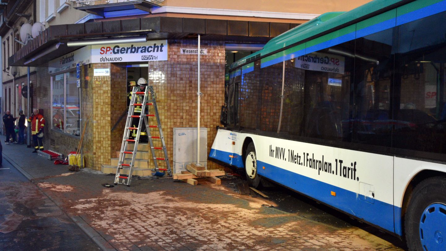 Einsatzkräfte von Feuerwehr, Polizei und Rettungsdiensten sichern in Eberbach die Unfallstelle, an der ein Schulbus am Morgen in eine Hauswand fuhr.