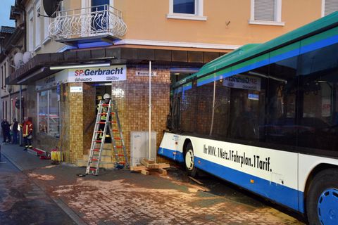 Einsatzkräfte von Feuerwehr, Polizei und Rettungsdiensten sichern in Eberbach die Unfallstelle, an der ein Schulbus am Morgen in eine Hauswand fuhr.