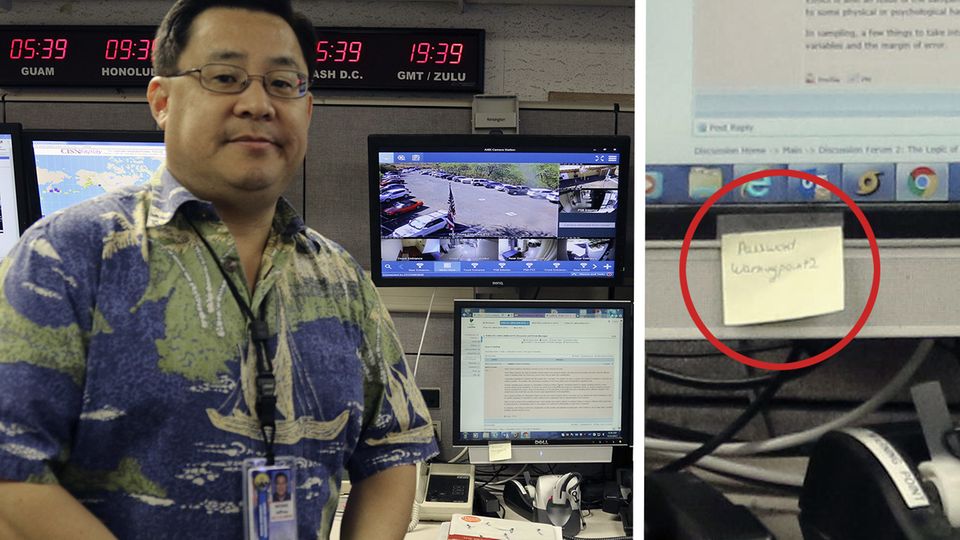 Ein asiatisch aussehender Mann mit Brille und Hawaii-Hemd steht vor einem Schreibtisch mit vier Monitoren