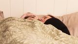 Polyamorie: Luke und Megan kuscheln im Bett.