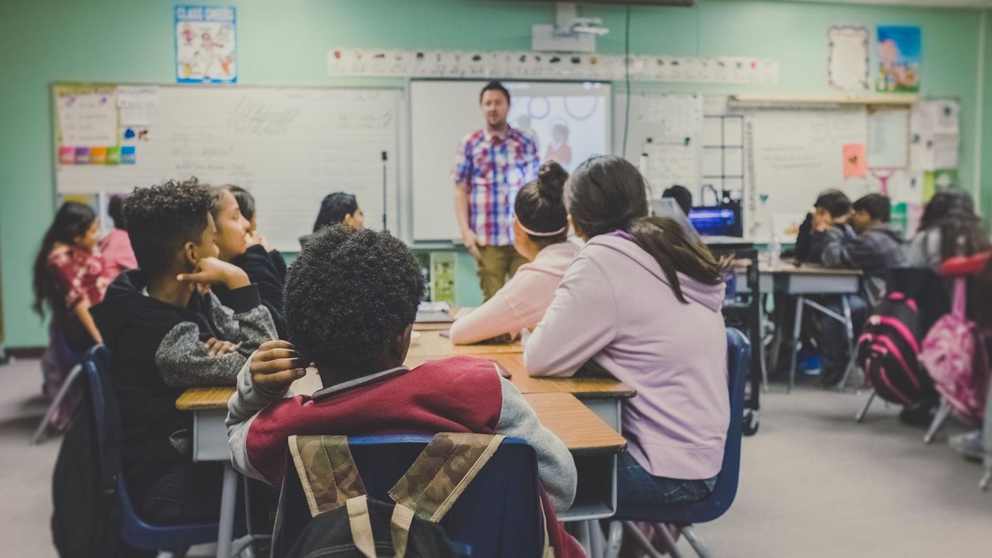 Kinder sitzen in der Schule im Unterricht und gucken nach vorne zum Lehrer.