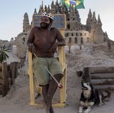 Der Brasilianer Marcio Mizael Matolias sitzt auf einem Holzstuhl vor seiner Strandburg in Rio.