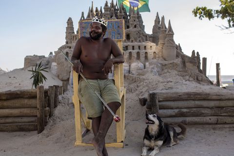 Der Brasilianer Marcio Mizael Matolias sitzt auf einem Holzstuhl vor seiner Strandburg in Rio.