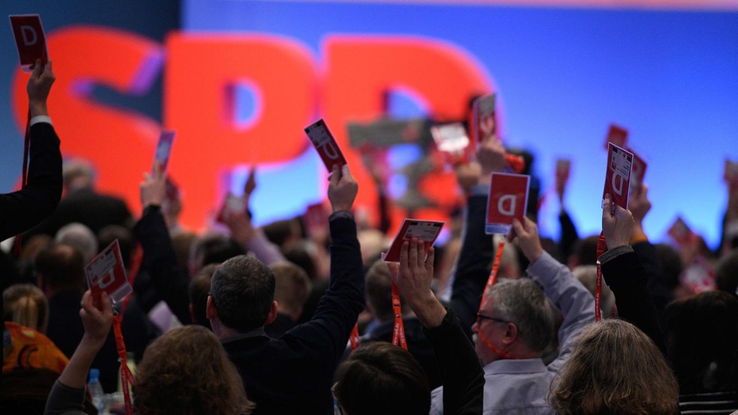 Vor einer blau beleuchteten Wand und großem "SPD" recken Delegierte auf dem Sonderparteitag ihre Abstimmungskarten hoch