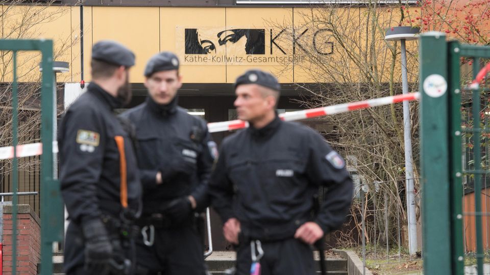 Käthe-Kollwitz-Gesamtschule Lünen Drei Polizisten stehen vor dem Schultor der Käthe-Kollwitz-Gesamtschule in Lünen, hinter ihnen ein sandgelbes Gebäude