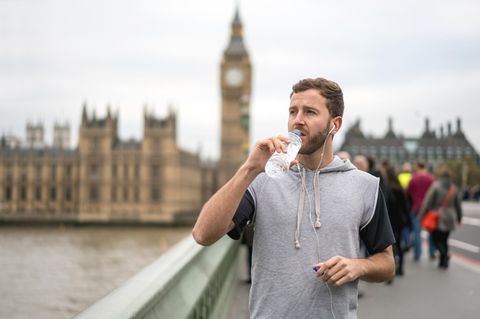 Ein Jogger steht vor dem Big Ben und trinkt aus einer Plastikflasche