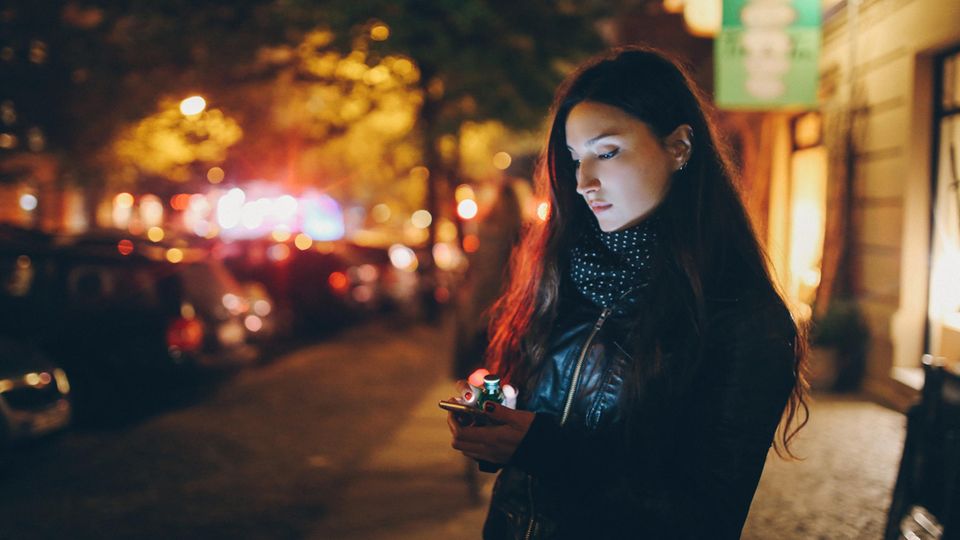 Heimwegtelefon: eine Frau steht nachts alleine auf der Straße