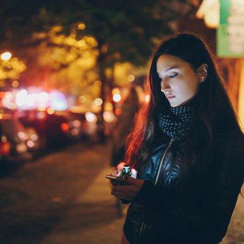 Heimwegtelefon: eine Frau steht nachts alleine auf der Straße