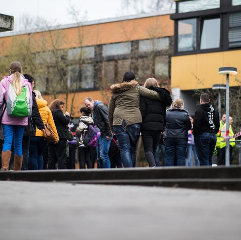 Vor der Käthe-Kollwitz-Gesamtschule in Lünen stehen Polizisten, Schülerinnen und Schüler, einige halten sich gegenseitig im Arm