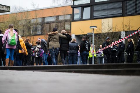 Vor der Käthe-Kollwitz-Gesamtschule in Lünen stehen Polizisten, Schülerinnen und Schüler, einige halten sich gegenseitig im Arm