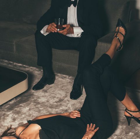 Ein älterer Herr sitzt im Anzug auf einer Couch, davor liegt eine junge Frau auf dem Rücken vor ihm (Symbolfoto)