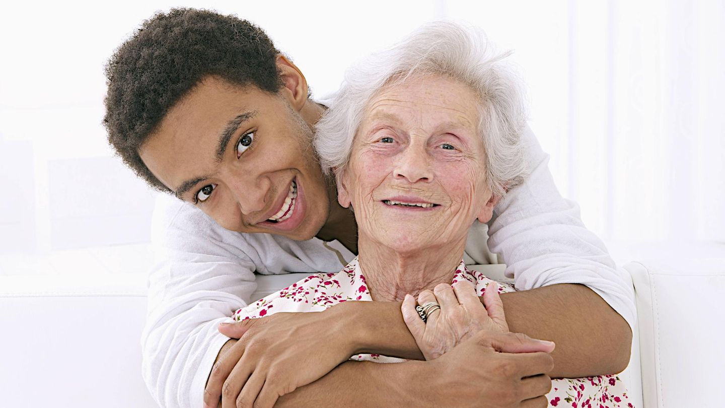 Eine Oma wird von ihrem Enkel liebevoll umarmt