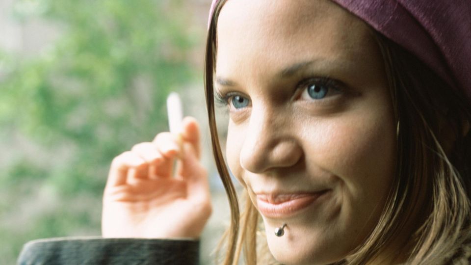 Ein Mädchen raucht mit zufriedenem Gesichtsausdruck eine Zigarette