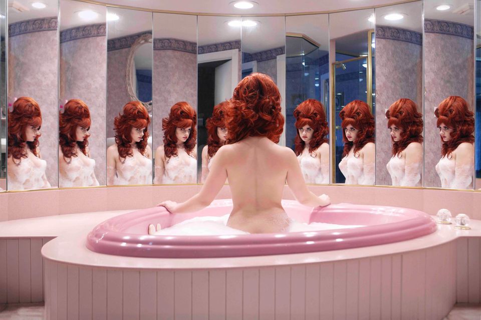 Eine nackte Frau sitzt in einer herzförmigen Badewanne in einer Honeymoon Suite