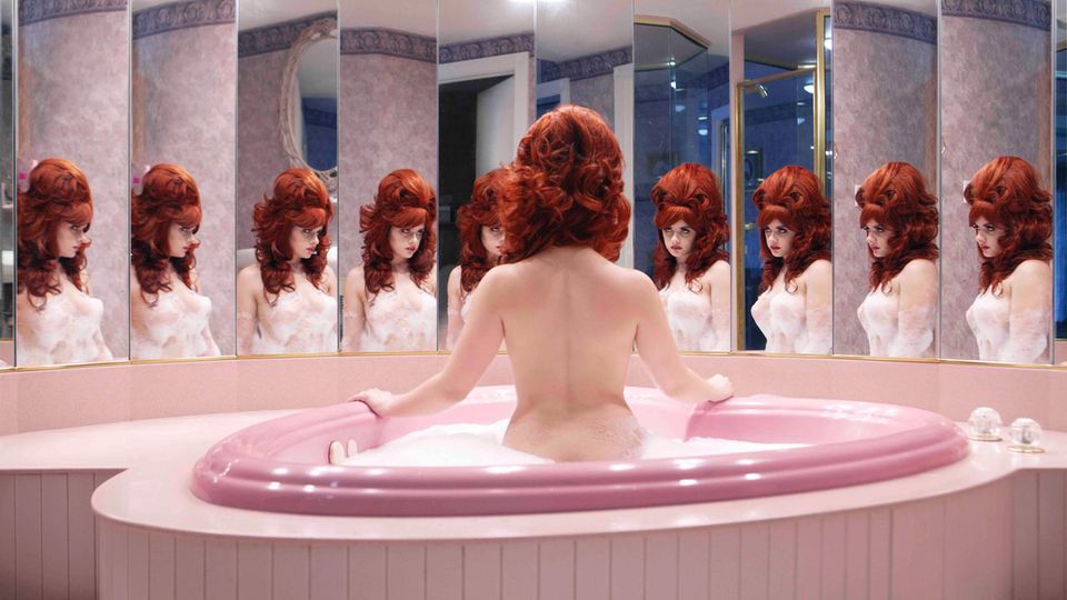 Eine nackte Frau sitzt in einer herzförmigen Badewanne in einer Honeymoon Suite
