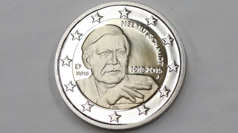 Auf einer Zwei-Euro-Münze liegt auf grauem Untergrund. Auf der Münze ist Altkanzler Helmut Schmidt zu sehen - ohne Zigarette