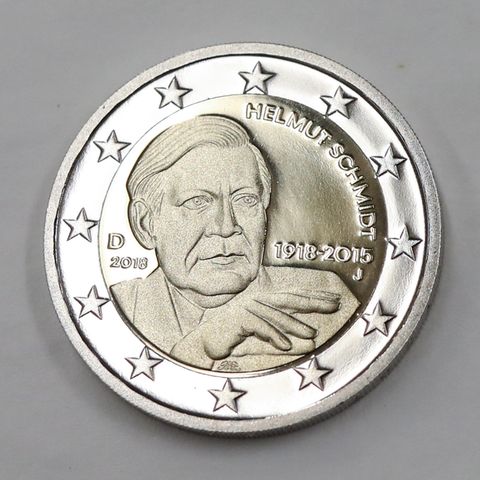 Auf einer Zwei-Euro-Münze liegt auf grauem Untergrund. Auf der Münze ist Altkanzler Helmut Schmidt zu sehen - ohne Zigarette