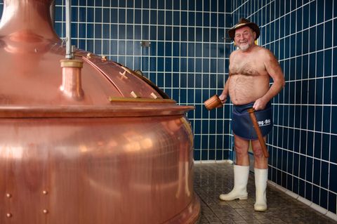 Bierbrauer Jürgen Hopf aus Oberfranken steht nur emit Schürze, Hut und Gummistiefel bekleidet in der Lang-Bräu-Brauerei.