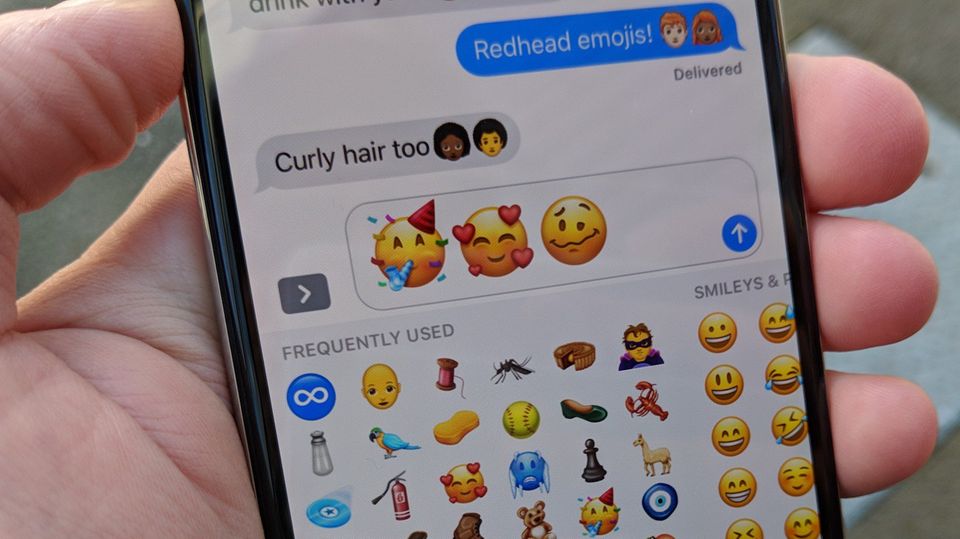 Ein Smartphone mit Emojis auf dem Display in einer Hand