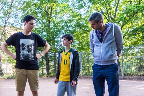 Michel Abdollahi steht mit zwei Jugendlichen auf einem Bolzplatz