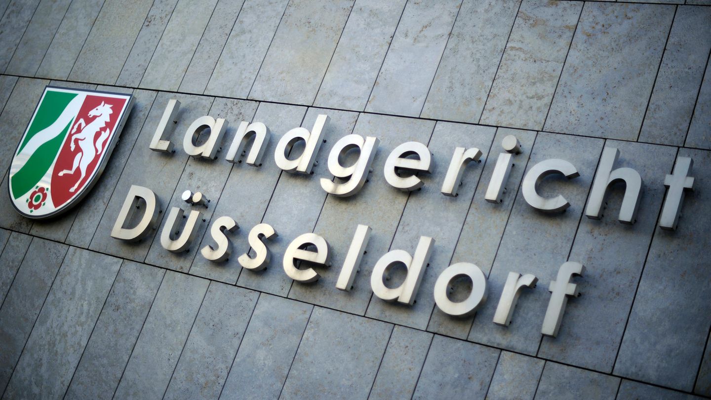 Auf einer grauen Steinfassade ist ein Schild mit dem Wappen von Nordrhein-Westfalen und der Schriftzug "Landgericht Düsseldorf"