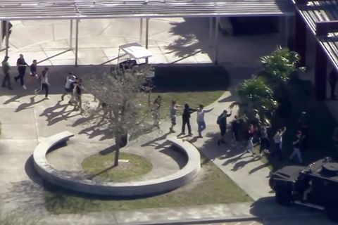 In einer Reihe überqueren Schüler mit erhobenen Händen den Schulhof der Marjory Stoneman Douglas High School
