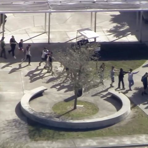 In einer Reihe überqueren Schüler mit erhobenen Händen den Schulhof der Marjory Stoneman Douglas High School