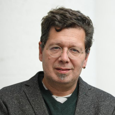 Mit Seitenscheitel und runder Brille blickt der Schriftsteller Franzobel in die Kamera. Er trägt ein Wolljackett