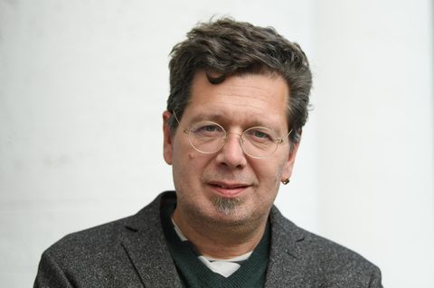 Mit Seitenscheitel und runder Brille blickt der Schriftsteller Franzobel in die Kamera. Er trägt ein Wolljackett