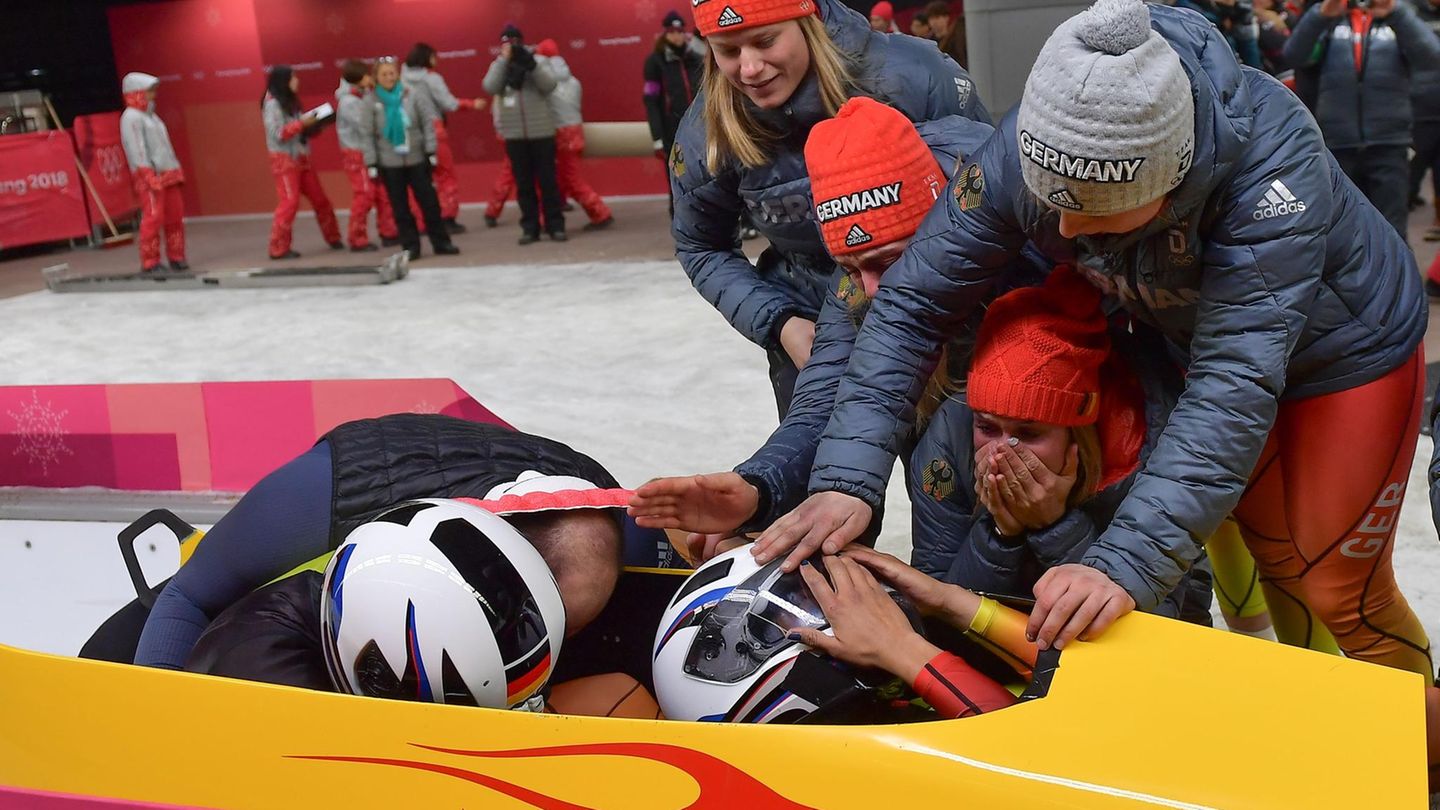 Überwältigt: Die deutsche Bobpilotin Miariama Jamanka schlägt die Hände vor den Helm, Anschieberin Lisa Buckwitz wird umarmt - es ist Gold. Der Sieg ist vor allem Jamankas exzellenten Fahrkünsten zu verdanken, die den Bob nahezu fehlerlos durch den anspruchsvollen Eiskanal steuerte.