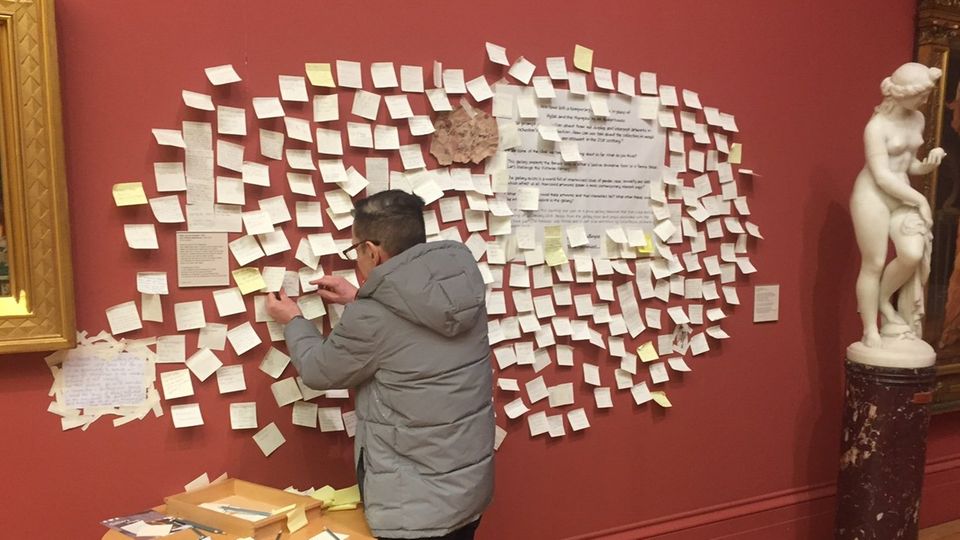 Ein Mann klebt eine Haftnotiz an die Museumswand in der Manchester Art Gallery.